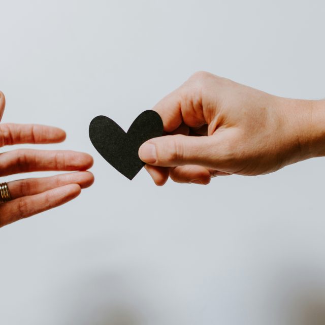 A picture depicting two people holding a heart shaped piece of paper